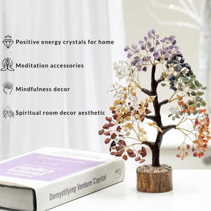 Peut inclure: Un arbre en cristal avec sept cristaux de couleurs diff&eacute;rentes, dont l'am&eacute;thyste, le quartz clair, l'aventurine verte, le jaspe rouge, la citrine, la rose quartz et l'&oelig;il de tigre. L'arbre est sur une base en bois et est entour&eacute; d'une surface blanche.