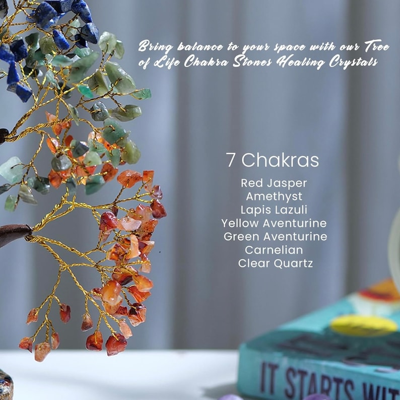 Peut inclure: Un arbre en fil de fer dor&eacute; d&eacute;cor&eacute; de sept pierres de chakra. Les pierres sont en jaspe rouge, am&eacute;thyste, lapis-lazuli, aventurine jaune, aventurine verte, cornaline et quartz clair. L'arbre est pos&eacute; sur une surface blanche avec un livre qui dit "IT STARTS WIT" en arri&egrave;re-plan.