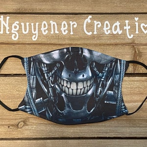 May include: A black face mask with a graphic of a robotic skull with a menacing grin. The mask has adjustable ear loops.