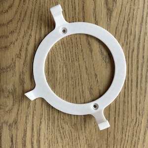 Könnte beinhalten: Weißer Kunststoffring mit drei Laschen, zum Befestigen einer Leuchte.