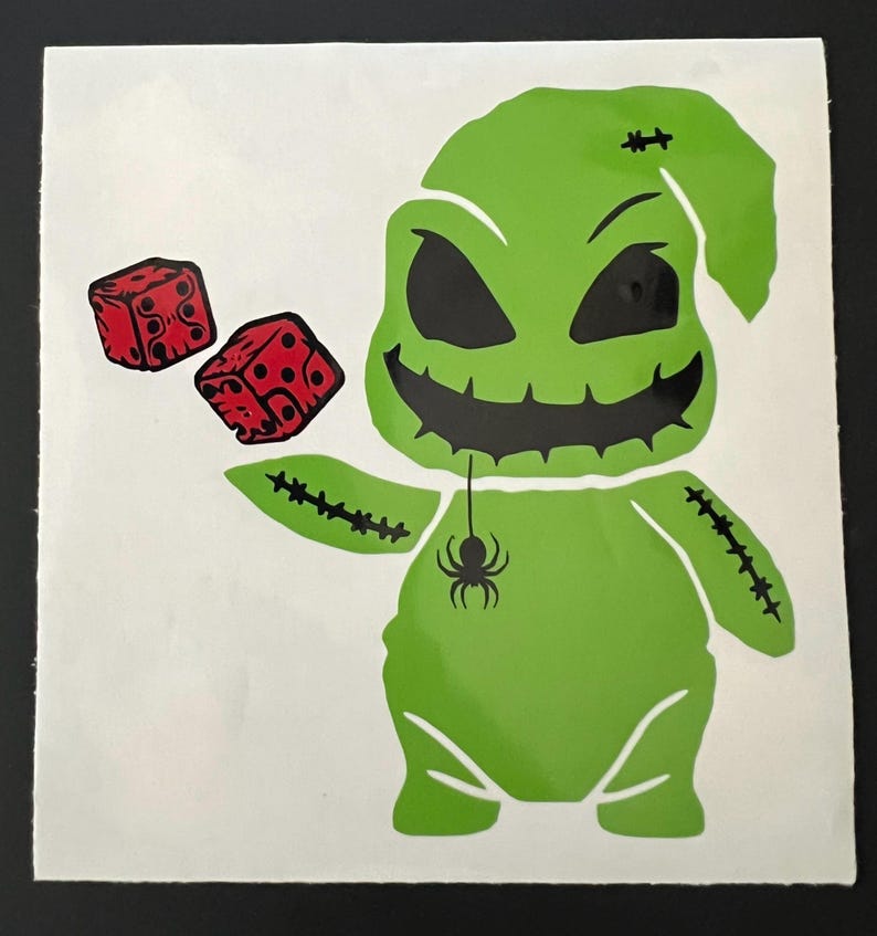May include: Green cartoon character with a stitched-up body and a spider hanging from its neck. The character is holding two red dice in its hands.