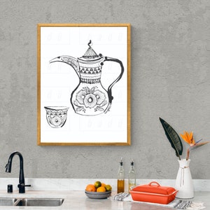 Può includere: Un disegno in bianco e nero di una tradizionale caffettiera araba e una tazza. La caffettiera ha un corpo rotondo con un beccuccio lungo e un manico. La tazza è piccola e rotonda. Il disegno è incorniciato in una cornice dorata e appeso a un muro grigio.