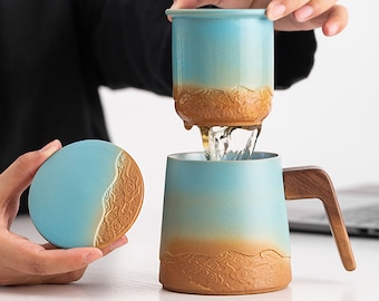May include: A blue and brown ceramic teacup with a wooden handle and a matching lid. The teacup has a textured design and is being used to brew tea.