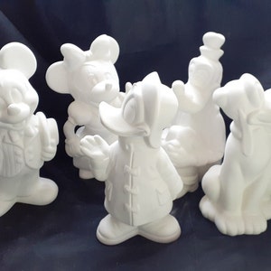 May include: Five white ceramic figurines of popular Disney characters: Mickey Mouse, Minnie Mouse, Donald Duck, Goofy, and Pluto. The figurines are all in a standing position and are ready to be painted.