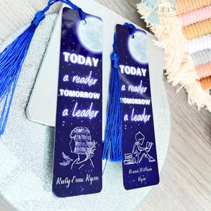 Puede incluir: Dos marcapáginas azules y plateados con un diseño de luna y estrellas. Los marcapáginas presentan el texto "Hoy un lector, mañana un líder". Un marcapáginas tiene una niña leyendo un libro y el nombre "Ruby Esme Ryan" en la parte inferior. El otro marcapáginas tiene un niño leyendo un libro y el nombre "Renna Willkan Ryan" en la parte inferior.