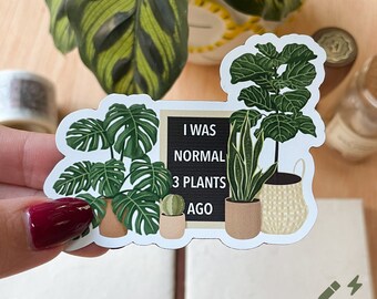 May include: A white sticker with a black chalkboard that says "I was normal 3 plants ago". The sticker features illustrations of three potted plants: a monstera, a snake plant, and a fiddle leaf fig.