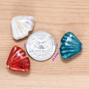 May include: Three ceramic shell-shaped beads in red, white, and blue. The beads are approximately 2.4 cm in diameter and are shown next to a US quarter for size comparison.