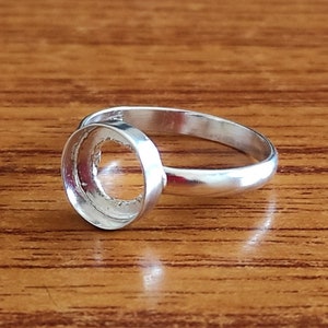 Puede incluir: Un anillo de plata con un engaste redondo. El engaste está vacío y listo para ser rellenado con una piedra u otro adorno.
