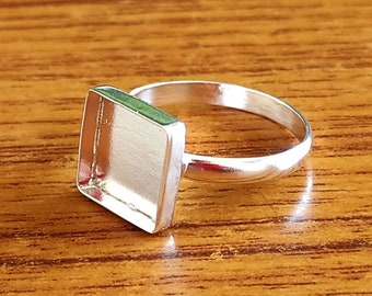 May include: A silver ring with a square-shaped bezel setting. The bezel is empty and ready to be filled with a stone or other embellishment.