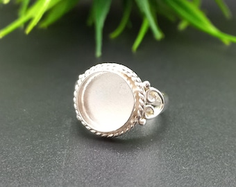 Könnte beinhalten: Silberring mit einer runden Fassung für einen Cabochon-Stein. Die Fassung hat einen seilartigen Rand.