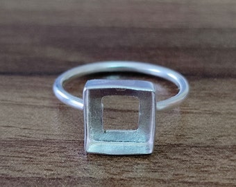 May include: A silver ring with a square bezel setting. The bezel is open and ready to hold a stone or other embellishment.