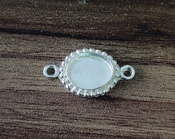 May include: Silver oval-shaped pendant with a beaded edge and two jump rings. The pendant is blank and ready for customization.