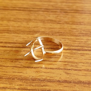 May include: A gold-toned ring setting with a teardrop-shaped opening for a gemstone. The setting has six prongs to hold the stone in place.