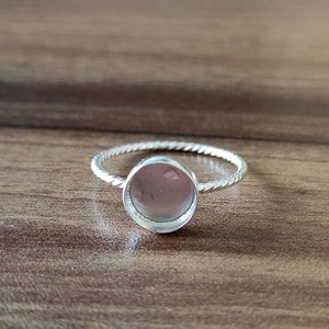 Può includere: Un anello d'argento con una montatura rotonda a cabochon. La fascia dell'anello è attorcigliata e ha una finitura lucida.