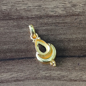 May include: A gold pendant shaped like a teardrop with a small loop at the top for attaching to a chain.