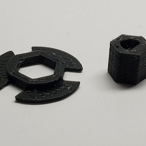 Puede incluir: Una tuerca hexagonal de plástico negro y una llave de plástico negro con tres brazos.