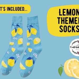 May include: A pair of light blue socks with a lemon theme. The socks feature a pattern of yellow lemons, lemon slices, and small white flowers. The text "Lemon Themed Socks" is displayed in a yellow bubble.
