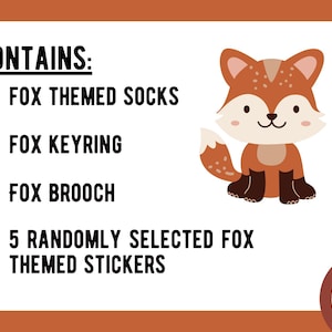 May include: A white rectangular card with orange borders featuring a cartoon fox illustration and black text that reads: CONTAINS: FOX THEMED SOCKS, FOX KEYRING, FOX BROOCH, 5 RANDOMLY SELECTED FOX THEMED STICKERS. A circular logo with text is in the corner.