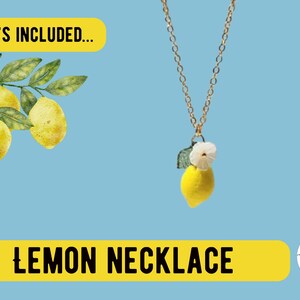 May include: A gold chain necklace with a lemon pendant. The pendant is a yellow lemon with a white flower and green leaf. The text "Lemon Necklace" is displayed on a yellow banner.
