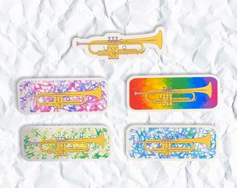 May include: Four trumpet stickers with different colourful backgrounds. The stickers feature a gold trumpet with a silver bell and valves. The backgrounds include a rainbow, pink and purple, green and yellow, and blue and white.