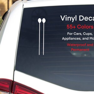 May include: White vinyl decal of two parallel lines with a circle at the top of each line. The decal is on the back window of a white car. The text "Vinyl Decal 55+ Colors For Cars, Cups, Appliances, and More Waterproof and Permanent" is printed in red on the window.