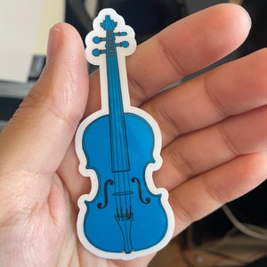 Puede incluir: Una pegatina de vinilo azul de un viol&iacute;n con cuerdas negras y un contorno blanco.