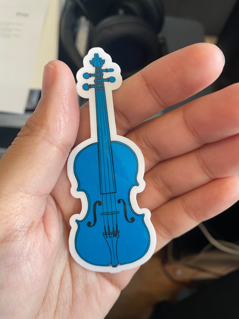 Puede incluir: Una pegatina de vinilo azul de un viol&iacute;n con cuerdas negras y un contorno blanco.
