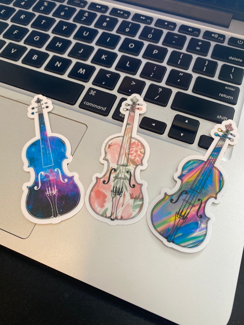 Puede incluir: Tres pegatinas de vinilo de violines con diferentes dise&ntilde;os. Un viol&iacute;n tiene un dise&ntilde;o de galaxia, otro tiene un dise&ntilde;o floral y el tercero tiene un dise&ntilde;o hologr&aacute;fico.