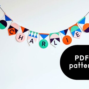 May include: A colorful felt banner with geometric shapes and the name "CHARLIE" spelled out in black letters. The banner is hanging on a white wall. PDF pattern.