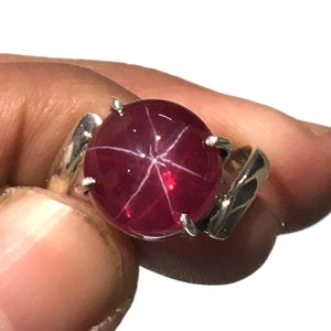 Peut inclure: Une bague en argent avec une grande pierre précieuse de rubis étoilé rouge ronde.