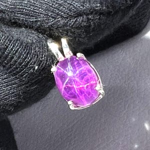 May include: A silver pendant featuring a purple oval gemstone. The gemstone has a distinctive, natural pattern.