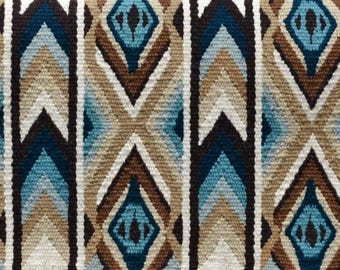 May include: A brown, blue, and beige patterned saddle blanket with a geometric design.