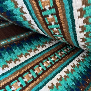 Pode incluir: Close-up de um tecido tecido com um padr&atilde;o repetitivo de listras marrons, brancas, azul-petr&oacute;leo e verdes. O tecido tem um aspecto texturizado e tecido &agrave; m&atilde;o.