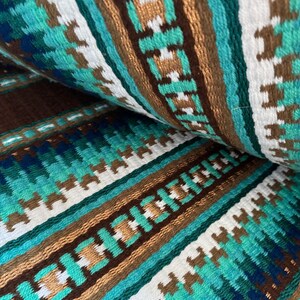 Pode incluir: Close-up de um tecido tecido com um padr&atilde;o repetitivo de listras marrons, brancas, azul-turquesa e verdes. O tecido tem um aspecto texturizado e tecido &agrave; m&atilde;o.