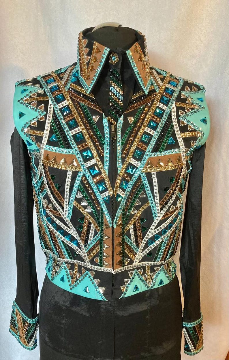 May include: A black show shirt with a turquoise, brown, gold, and green geometric pattern. The shirt has a zip fastening and long sleeves with matching cuffs.