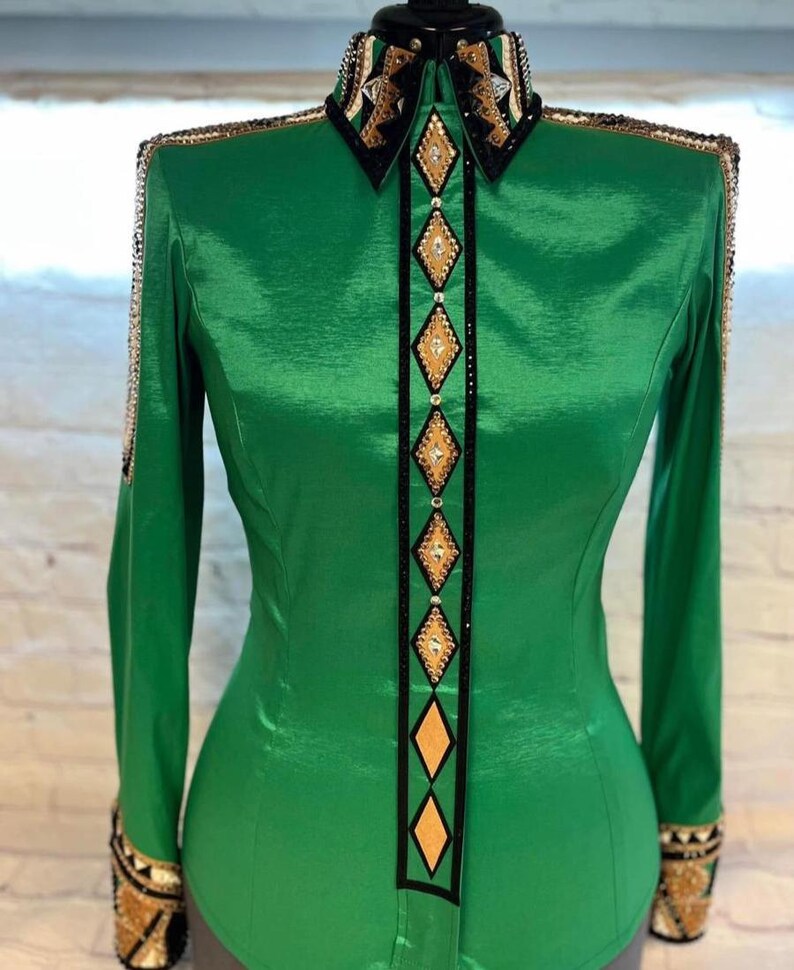 May include: A green long-sleeved shirt with a black and gold geometric design. The shirt has a pointed collar and a button-up front.