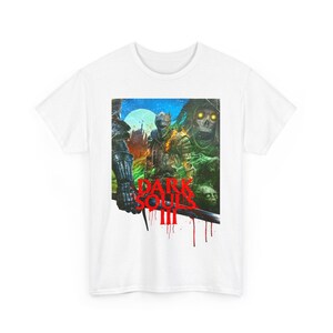 May include: White t-shirt featuring a graphic print of characters from the video game Dark Souls III. The graphic depicts a dark, fantasy setting with a red and white "Dark Souls III" logo.