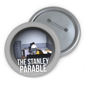 May include: A gray button with a white border and a picture of a man sitting at a desk in an office. The text "THE STANLEY PARABLE" is printed in white on the button.