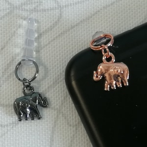 May include: Two elephant charms, one silver and one rose gold, attached to phone charms. The charms are on a white background.