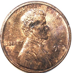 Può includere: Una moneta da un centesimo di dollaro statunitense color rame. Il dritto presenta un profilo di Abraham Lincoln, la parola "LIBERTY" e l'anno "1971". La moneta ha un aspetto usurato.