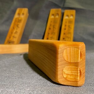 Puede incluir: Un conjunto de bloques de madera de color marr&oacute;n claro con forma rectangular y bordes redondeados. Cada bloque presenta dos hendiduras circulares en un extremo y una serie de peque&ntilde;as marcas circulares oscuras en el lateral con veta natural.