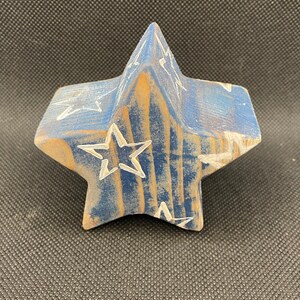 May include: A blue wooden star with white painted stars on it. The star is a 3D shape and has a rustic look.
