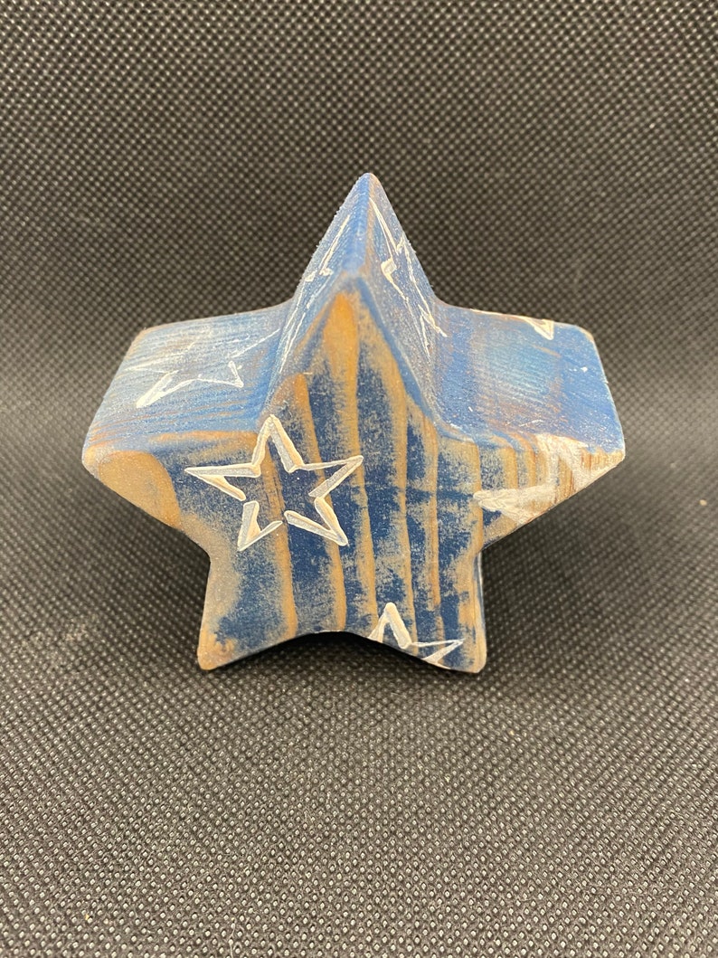May include: A blue wooden star with white painted stars on it. The star is a 3D shape and has a rustic look.