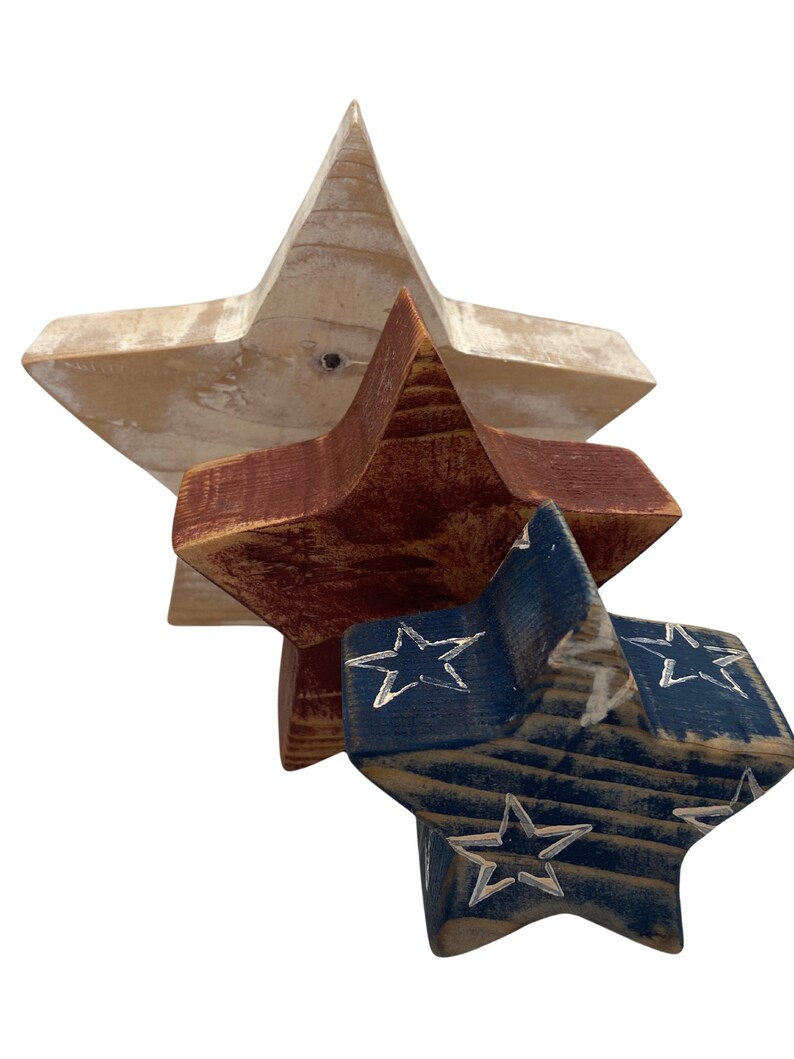 May include: Three wooden stars in red, white, and blue. The largest star is white, the middle star is red, and the smallest star is blue with white stars painted on it.