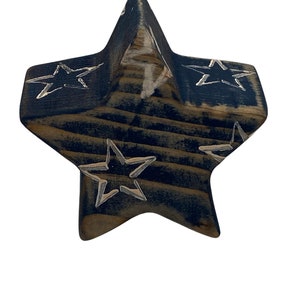 May include: A wooden star-shaped ornament painted in a dark blue color with white stars painted on the surface.