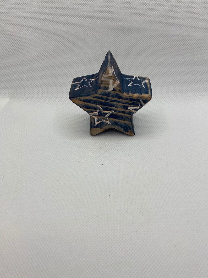 May include: A wooden star-shaped ornament painted in blue and white with a distressed finish. The star has a white star design carved into each point.