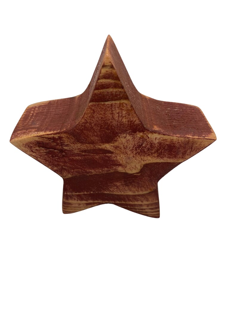 May include: A wooden star ornament painted in a deep red color with a rustic finish. The star is made of wood with visible grain and has a slightly distressed look.