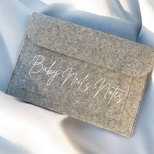 May include: Grey felt envelope with white text that reads "Baby Neil's Notes".