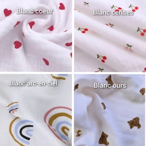 May include: Four white fabric squares with different patterns. The top left square has red hearts, the top right square has red cherries, the bottom left square has rainbow patterns, and the bottom right square has brown teddy bears.