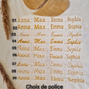 May include: A white fabric with nine rows of embroidered names, each row numbered 01 through 09. The names are Anna, Max, Emma, and Sophia. The text "Choix de police" is at the bottom of the fabric.